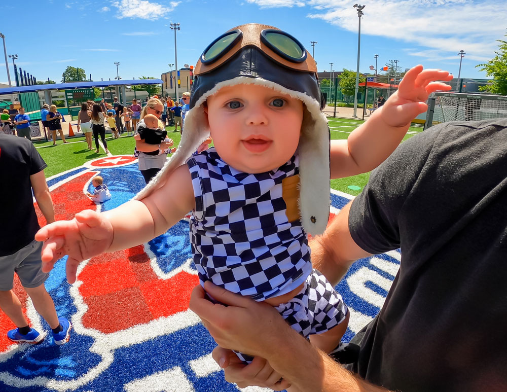 Baby wearing checkered flag-themed outfit in the Soccer Experience.